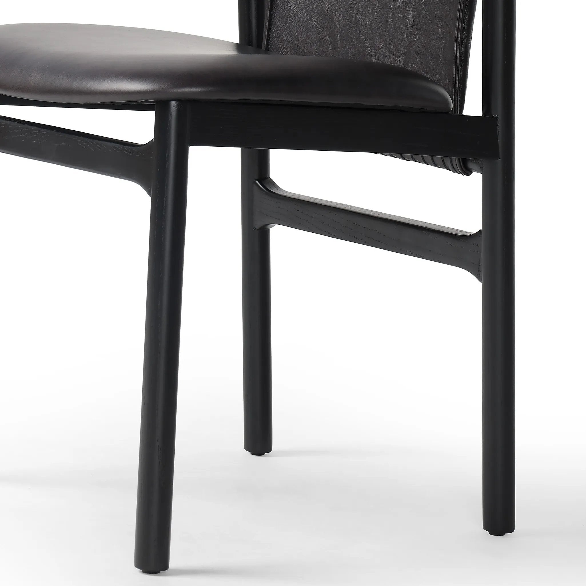 Featuring Baden Sonoma Black Dining Chair by Four Hands at Amethyst Home. Midcentury-inspired with its minimalist wooden frame, this armless dining chair features a low back and float-like seat upholstered in slightly distressed black top-grain leather exclusive to Four Hands. Leather wrap detailing for texture.Overall Dimensions: 19.75"w x 23.25"d x 32.2. Amethyst Home provides interior design, new home construction design consulting, vintage area rugs, and lighting in the Kansas City metro area.