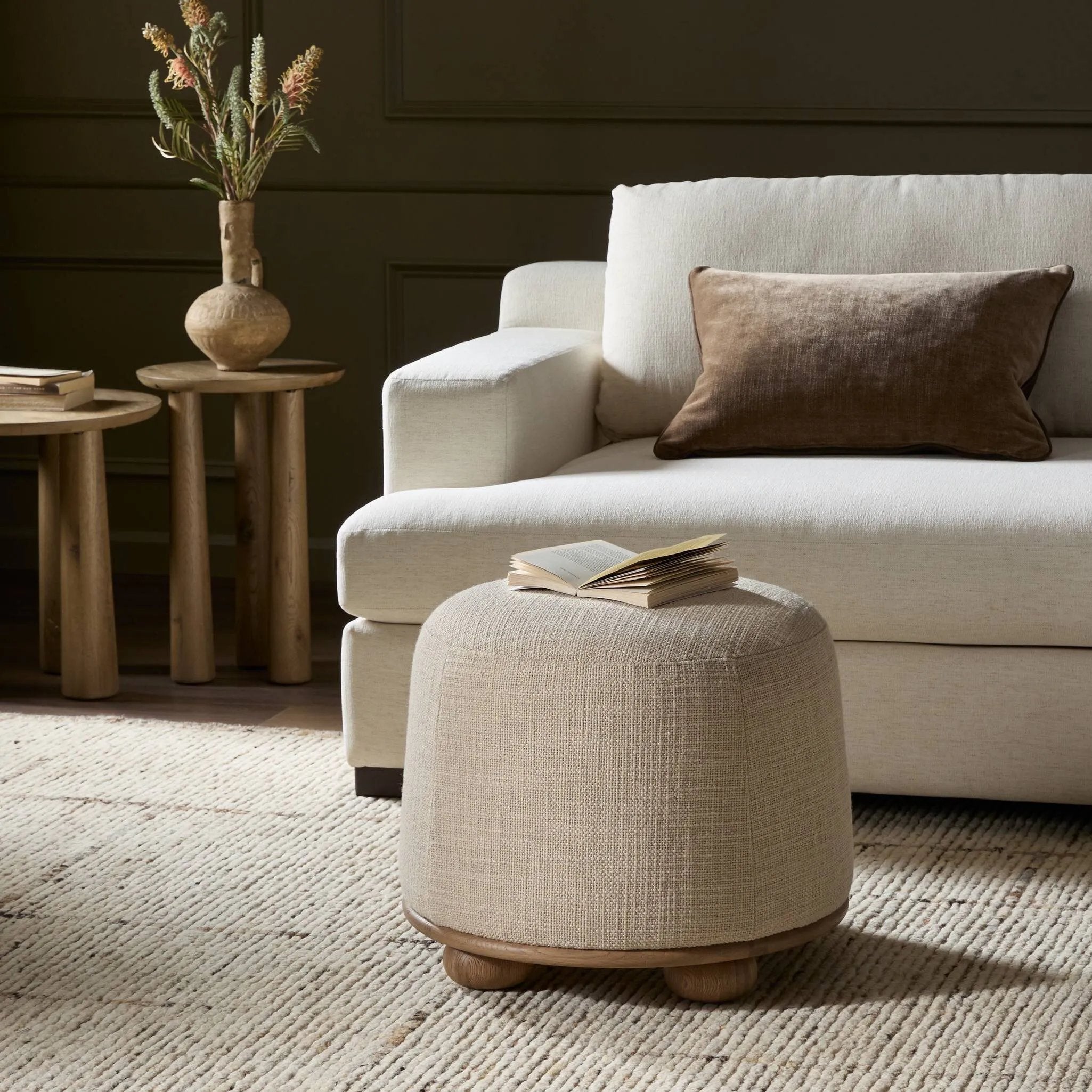 Featuring Bilbury Saxon Sand Ottoman by Four Hands at Amethyst Home. For an extra seat or propped feet, this welcoming ottoman features a subtly tapered shape and a rounded base with oak bun feet beneath. Crafted with soft foam cushioning and upholstered in a poly/wool blend fabric. Overall Dimensions: 22.00"w x 22.00"d x 18.50"h. Amethyst Home provides interior design, new home construction design consulting, vintage area rugs, and lighting in the Charlotte metro area.