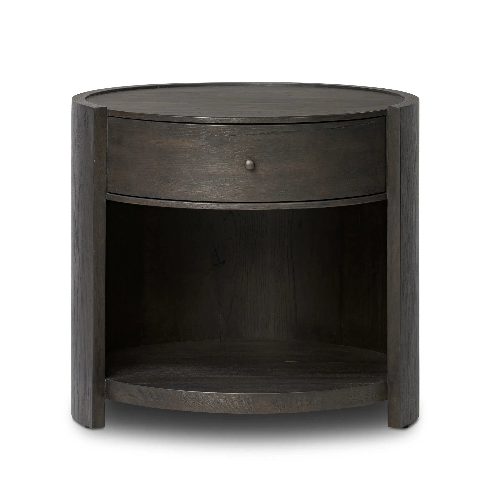 Rich contours bring character to the bedside. A round black-finished oak table has a spacious cubby and a single drawer with metal glides and a bronzed pull Amethyst Home provides interior design, new home construction design consulting, vintage area rugs, and lighting in the Boston metro area.