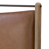 Slightly scooped top-grain leather tufting is bridged with metal bars in brushed brass for modern detailing. Aged smoked oak