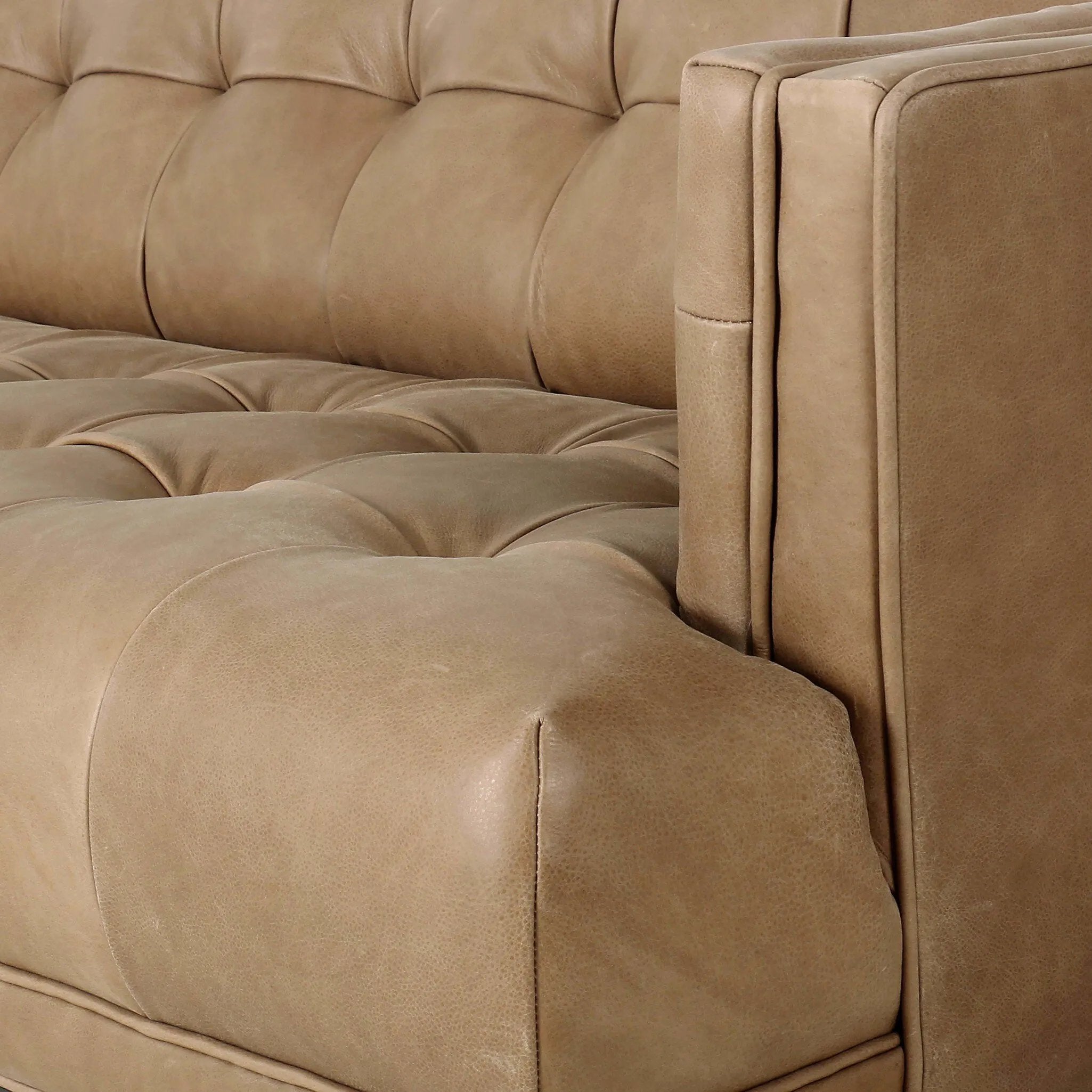 A modernized midcentury silhouette meets the traditional Chesterfield sofa, all in a compact profile perfect for smaller spaces. Top-grain leather in a tan hue, button tufting and a smooth touch bring deep comfort to lounging Amethyst Home provides interior design, new home construction design consulting, vintage area rugs, and lighting in the Tampa metro area.