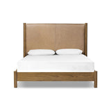 Rounded, chunky dowel legs in an amber oak finish frame the tan top-grain leather headboard of this simple-but-striking bed frame Amethyst Home provides interior design, new home construction design consulting, vintage area rugs, and lighting in the Austin metro area.