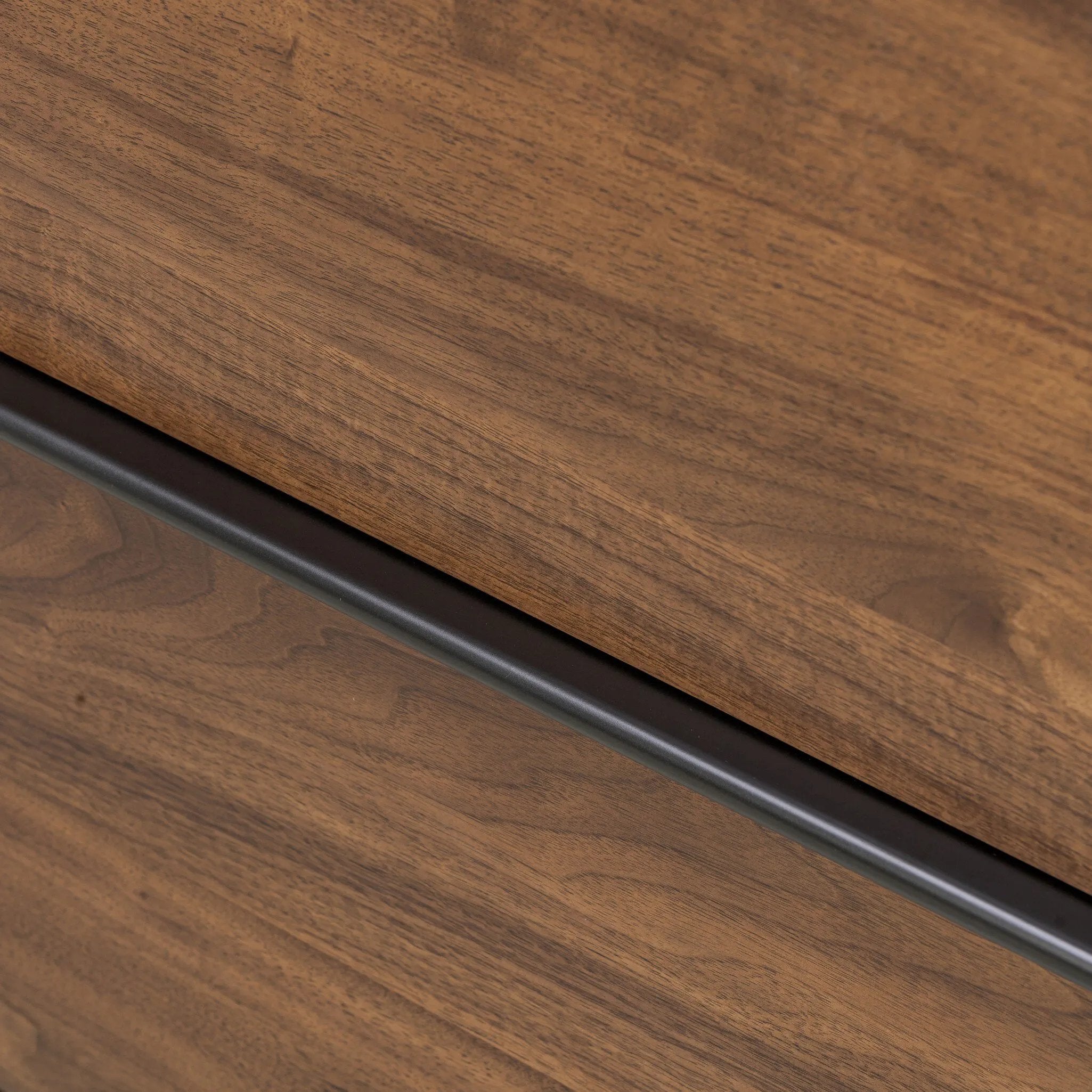 Dark brown walnut is aesthetically shaped with fluid, rounded corners on a ski leg base. The seamless design features six spacious drawers with metal bar hardware that runs along the tops of the drawers Amethyst Home provides interior design, new home construction design consulting, vintage area rugs, and lighting in the Kansas City metro area.