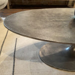 We love the oval shape of this Simone Coffee Table - Antique Nickel. The textural cast aluminum makes for a beautifully modern coffee table, with alluring highs and lows played up by a raw nickel finish. Great indoors or out; cover or store indoors during inclement weather and when not in use.  Overall Dimensions: 54.75"w x 29.25"d x 16.50"h