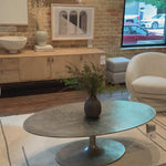 We love the oval shape of this Simone Coffee Table - Antique Nickel. The textural cast aluminum makes for a beautifully modern coffee table, with alluring highs and lows played up by a raw nickel finish. Great indoors or out; cover or store indoors during inclement weather and when not in use.  Overall Dimensions: 54.75"w x 29.25"d x 16.50"h