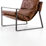 Featuring Emmett Sling Chair - Leather by Four Hands at Amethyst Home. Super stylish, effortlessly cool. Sling-style seating of tobacco-toned leather sits low and curved for a fresh take on a throwback form. Slim, gunmetal-finished iron framing ups the drama factor of an innately hip design.
Overall Dimensions: 29"W x 36"L x 29"HColors: Dakota Tobacco, Gunmet.  Amethyst Home provides interior design, new home construction design consulting, vintage area rugs, and lighting in the Boston metro area.