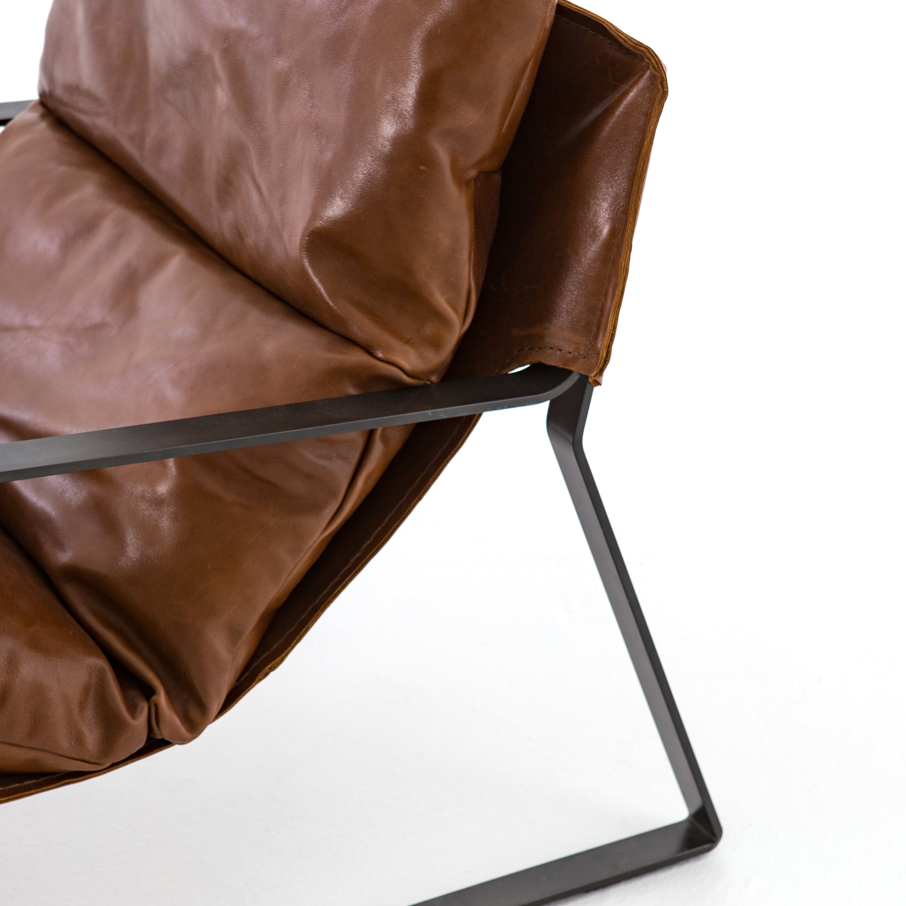 Featuring Emmett Sling Chair - Leather by Four Hands at Amethyst Home. Super stylish, effortlessly cool. Sling-style seating of tobacco-toned leather sits low and curved for a fresh take on a throwback form. Slim, gunmetal-finished iron framing ups the drama factor of an innately hip design.
Overall Dimensions: 29"W x 36"L x 29"HColors: Dakota Tobacco,.  Amethyst Home provides interior design, new home construction design consulting, vintage area rugs, and lighting in the Winter Garden metro area.