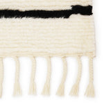Featuring Desouk Vendace Rug by Jaipur Living at Amethyst Home. The Desouk collection melds modern allure with the global vibes of Morocco. The Vendace hand-knotted rug showcases a geometric linear pattern with contrasting black and cream tones. This handcrafted rug boasts plush, cut wool pile that pairs beautifully with braided tassel details. Perfect for adding warmth to cozy bedrooms a. Amethyst Home provides interior design services, furniture, rugs, and lighting in the Kansas City metro area.