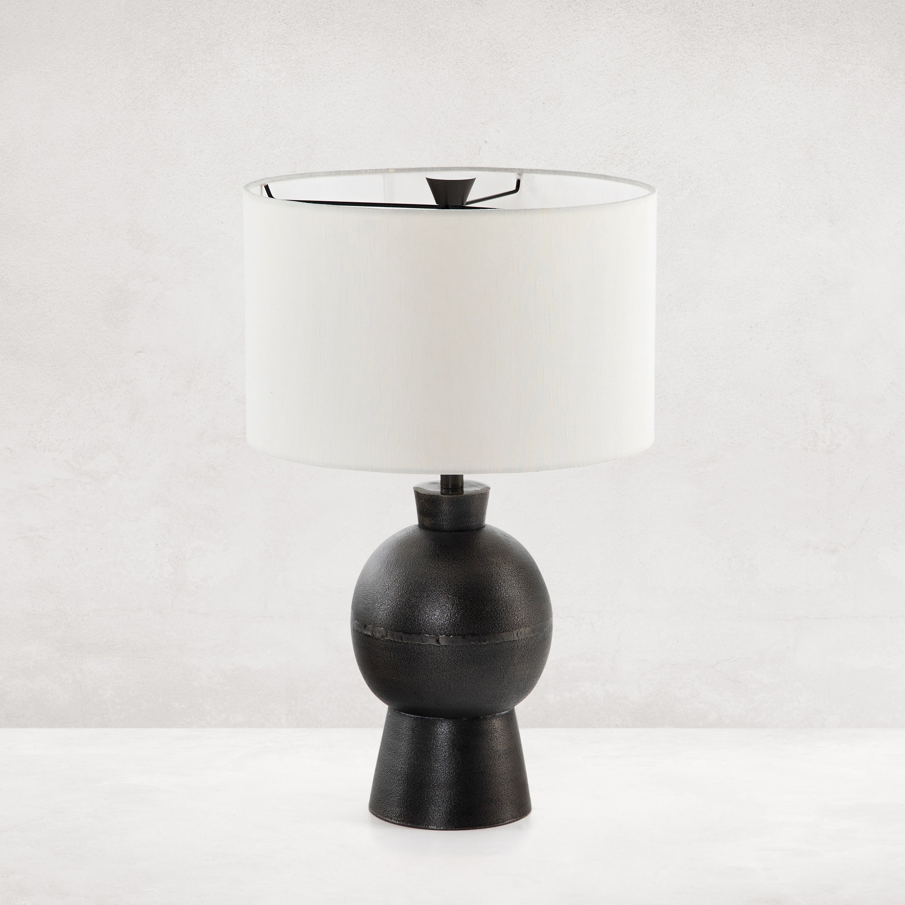 Featuring Kelita Textured Black Table Lamp by Four Hands at Amethyst Home. Textured black aluminum forms a shapely base to beautifully complement a white silk shade with this Kelita Textured Black Table Lamp. A beautiful lamp to place next your bed, sofa, or other area needing extra light.
Overall Dimensions: 16"W x 16"L x 25"H
Colors: Textured Black Alumi.  Amethyst Home provides interior design, new home construction design consulting, vintage area rugs, and lighting in the Park City metro area.