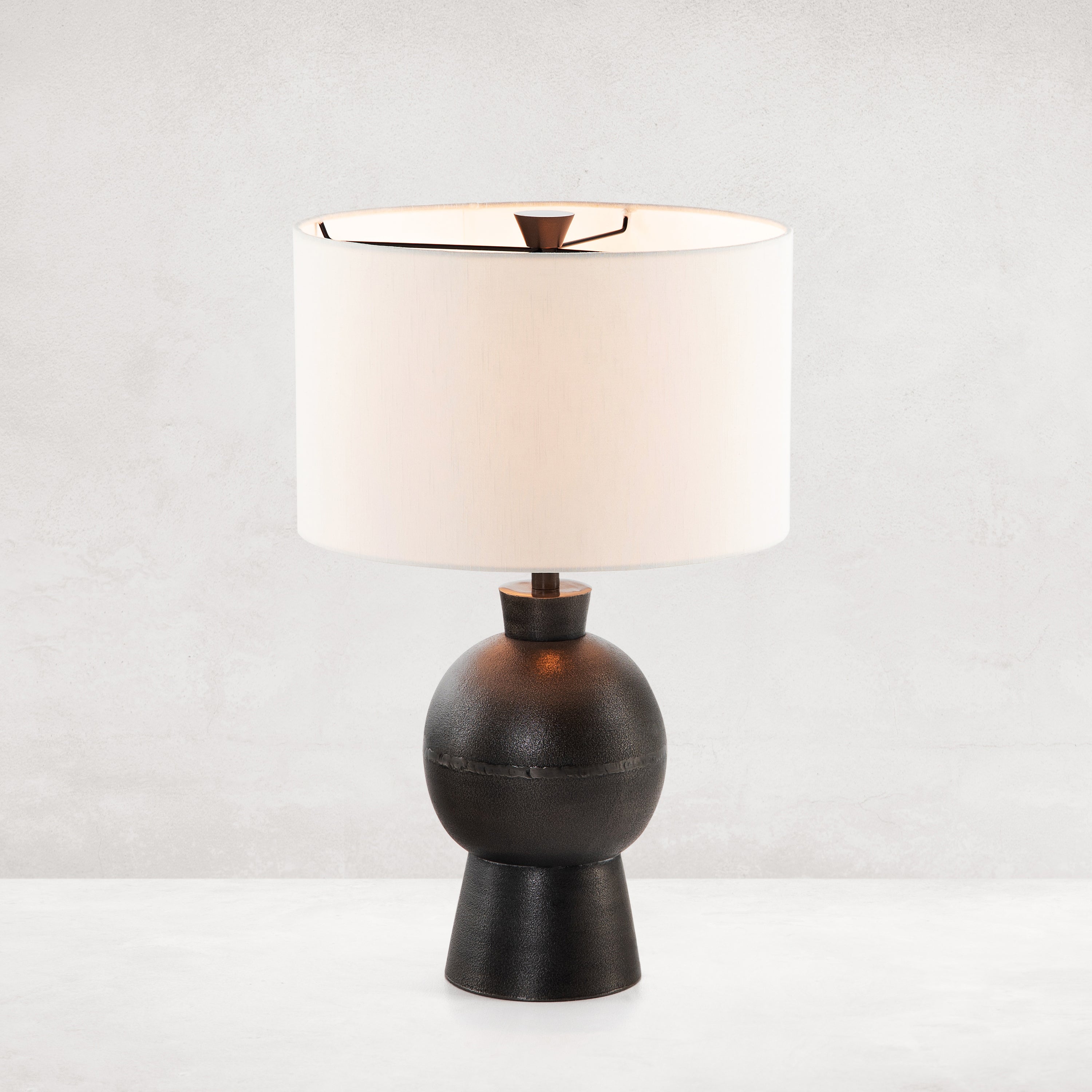 Featuring Kelita Textured Black Table Lamp by Four Hands at Amethyst Home. Textured black aluminum forms a shapely base to beautifully complement a white silk shade with this Kelita Textured Black Table Lamp. A beautiful lamp to place next your bed, sofa, or other area needing extra light.
Overall Dimensions: 16"W x 16"L x 25"H
Colors: Textured Black Aluminum.  Amethyst Home provides interior design, new home construction design consulting, vintage area rugs, and lighting in the Boston metro area.