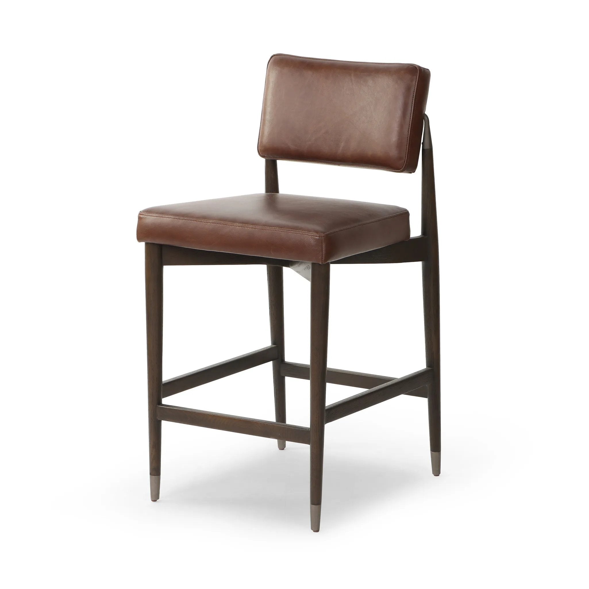 Eighties inspiration gone modern. With iron-dipped caps, tapered legs of solid oak frame this counter stool's seat and back, upholstered in brown top-grain leather. Slim wood stretchers add an airy vibe Amethyst Home provides interior design, new home construction design consulting, vintage area rugs, and lighting in the Dallas metro area.