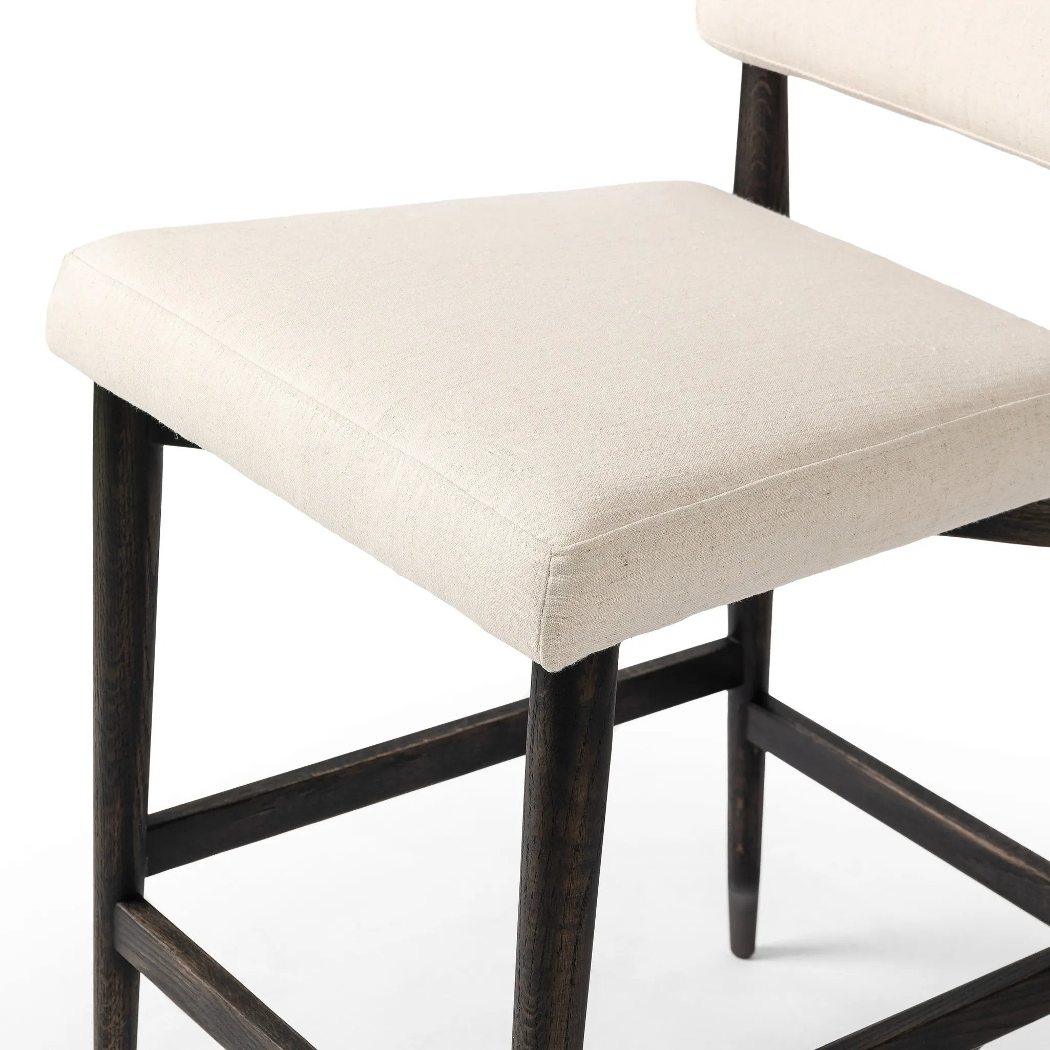 Featuring Anton Savile Flax Bar + Counter Stool by Four Hands at Amethyst Home. Eighties inspiration gone modern. With iron-dipped caps, tapered legs of solid oak frame this bar stool's seat and back, upholstered in light performance fabric. Slim wood stretchers add an airy vibe to this counter stool. Performance fabrics are specially created to withstand spill. Amethyst Home provides interior design, new home construction design consulting, vintage area rugs, and lighting in the Miami metro area.