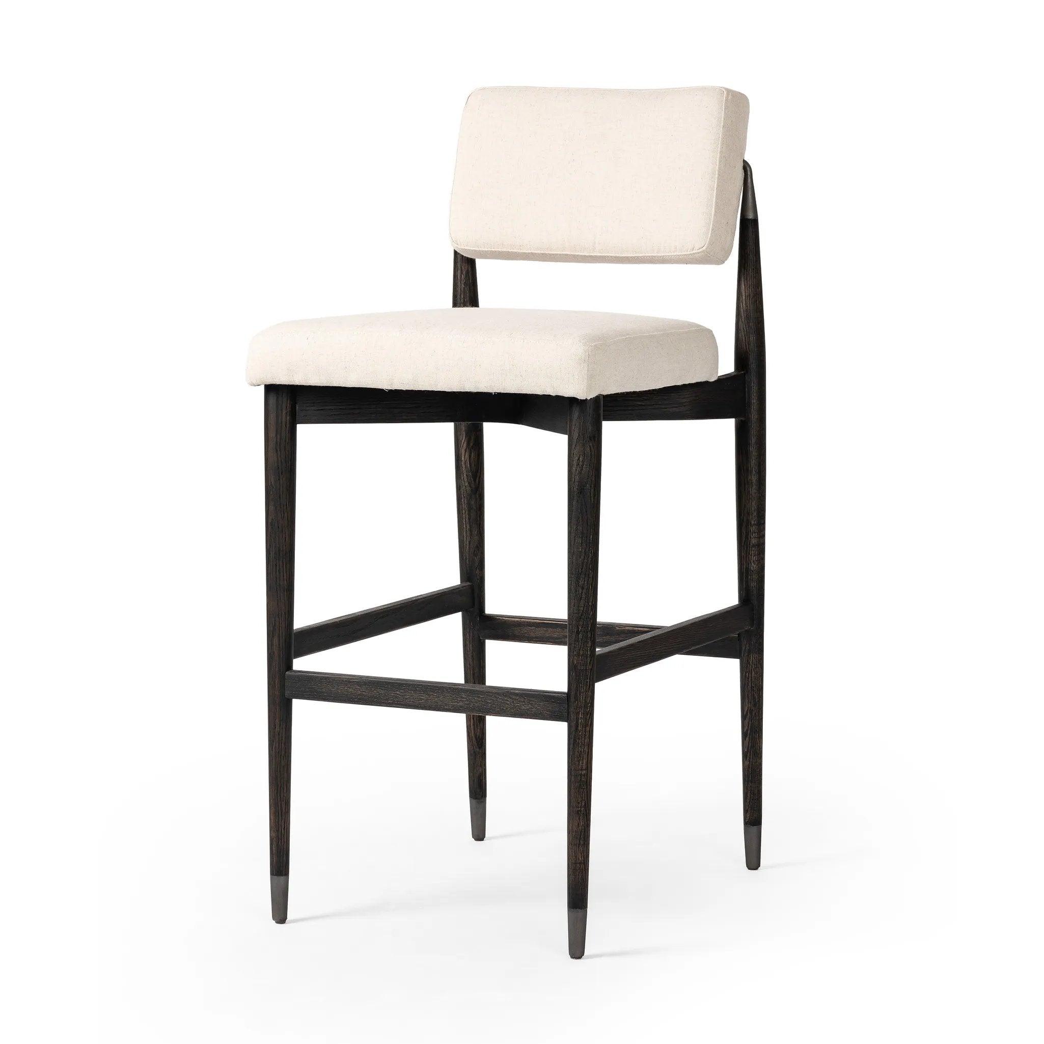 Featuring Anton Savile Flax Bar + Counter Stool by Four Hands at Amethyst Home. Eighties inspiration gone modern. With iron-dipped caps, tapered legs of solid oak frame this bar stool's seat and back, upholstered in light performance fabric. Slim wood stretchers add an airy vibe to this counter stool. Performance fabrics are specially created to withstand spill. Amethyst Home provides interior design, new home construction design consulting, vintage area rugs, and lighting in the Tampa metro area.