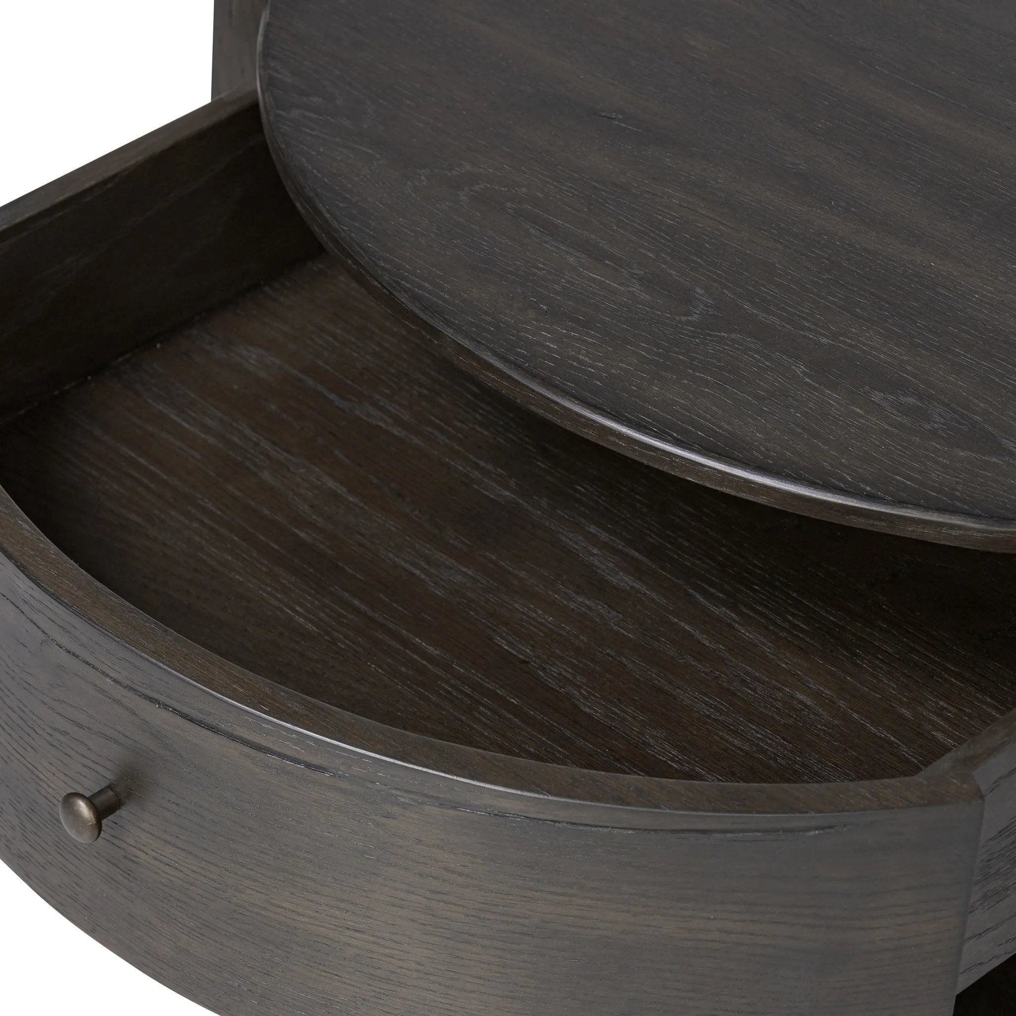 Rich contours bring character to the bedside. A round black-finished oak table has a spacious cubby and a single drawer with metal glides and a bronzed pull Amethyst Home provides interior design, new home construction design consulting, vintage area rugs, and lighting in the Los Angeles metro area.