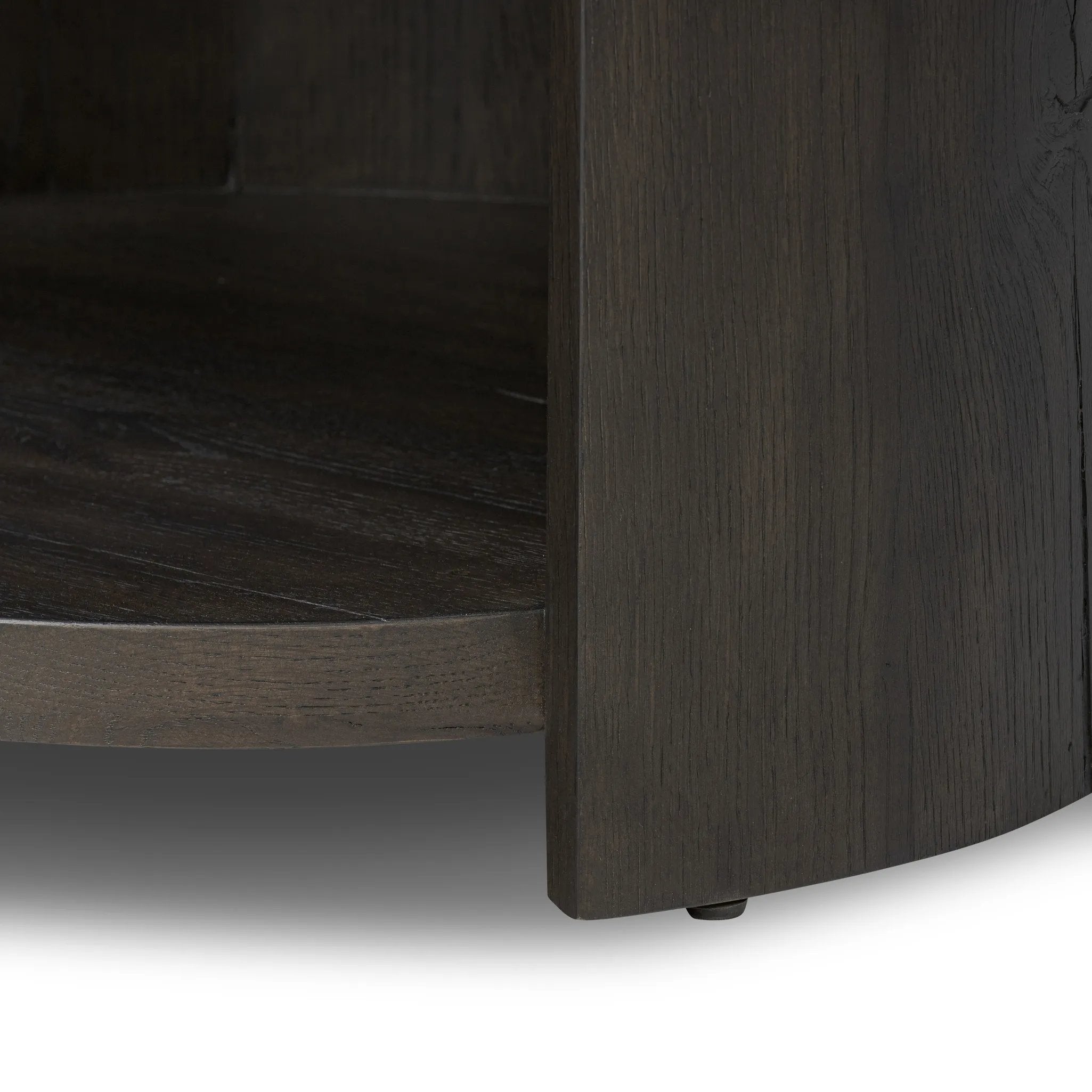Rich contours bring character to the bedside. A round black-finished oak table has a spacious cubby and a single drawer with metal glides and a bronzed pull Amethyst Home provides interior design, new home construction design consulting, vintage area rugs, and lighting in the Seattle metro area.