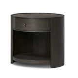 Rich contours bring character to the bedside. A round black-finished oak table has a spacious cubby and a single drawer with metal glides and a bronzed pull Amethyst Home provides interior design, new home construction design consulting, vintage area rugs, and lighting in the Washington metro area.