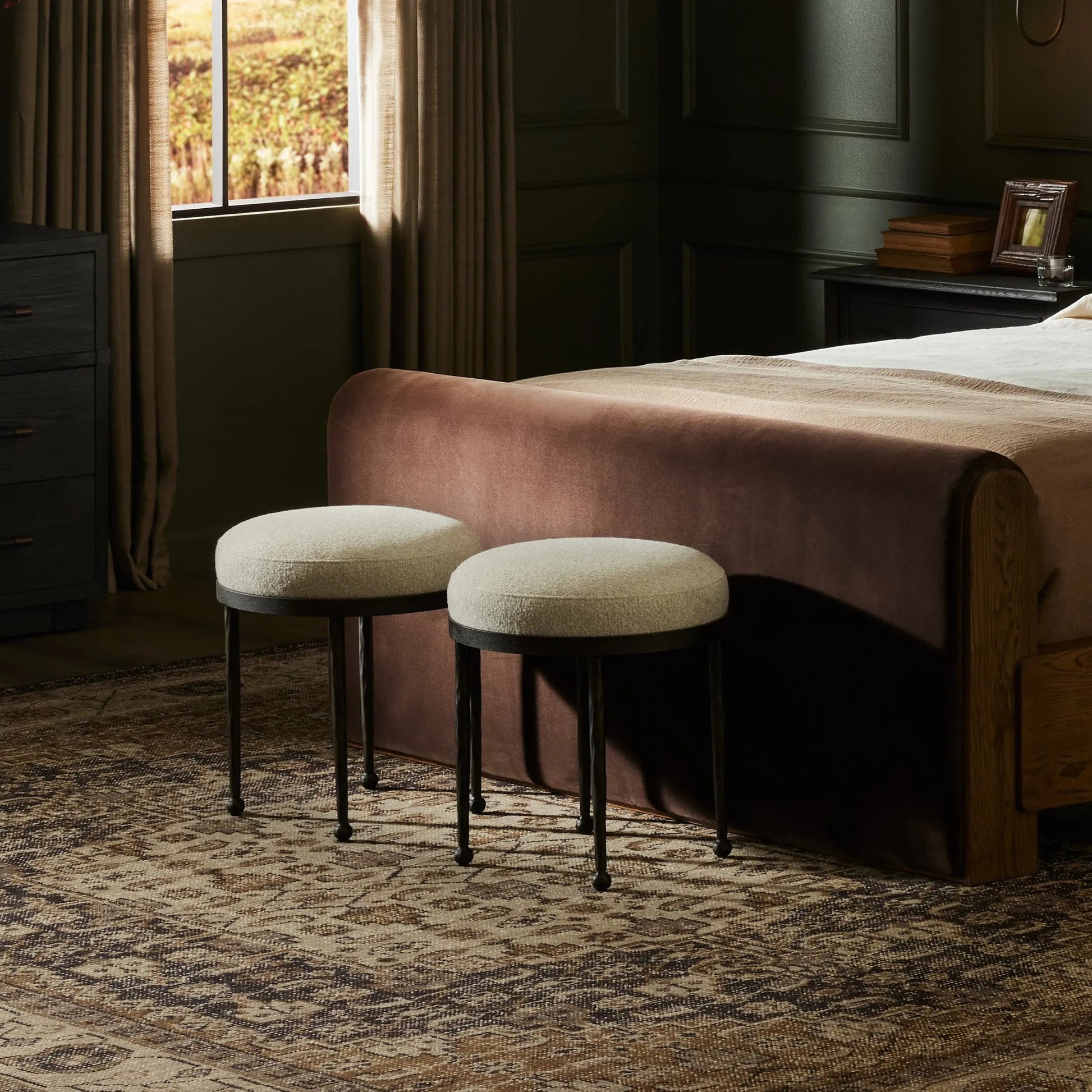 Work midcentury vibes into any space with a pared-back accent stool that doubles as a cocktail ottoman. Wrough iron legs finished in a hammered bronze pair with a simple rounded seat upholstered in a texture-rich fabric, with S-spring suspension for comfort and structure Amethyst Home provides interior design, new home construction design consulting, vintage area rugs, and lighting in the Austin metro area.