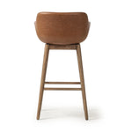A midcentury-inspired counter stool gets refreshed with a modern memory swivel and chestnut top-grain leather. Slim, tapered oak legs balance a curved seat Amethyst Home provides interior design, new home construction design consulting, vintage area rugs, and lighting in the Austin metro area.