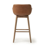 A midcentury-inspired counter stool gets refreshed with a modern memory swivel and chestnut top-grain leather. Slim, tapered oak legs balance a curved seat Amethyst Home provides interior design, new home construction design consulting, vintage area rugs, and lighting in the Austin metro area.