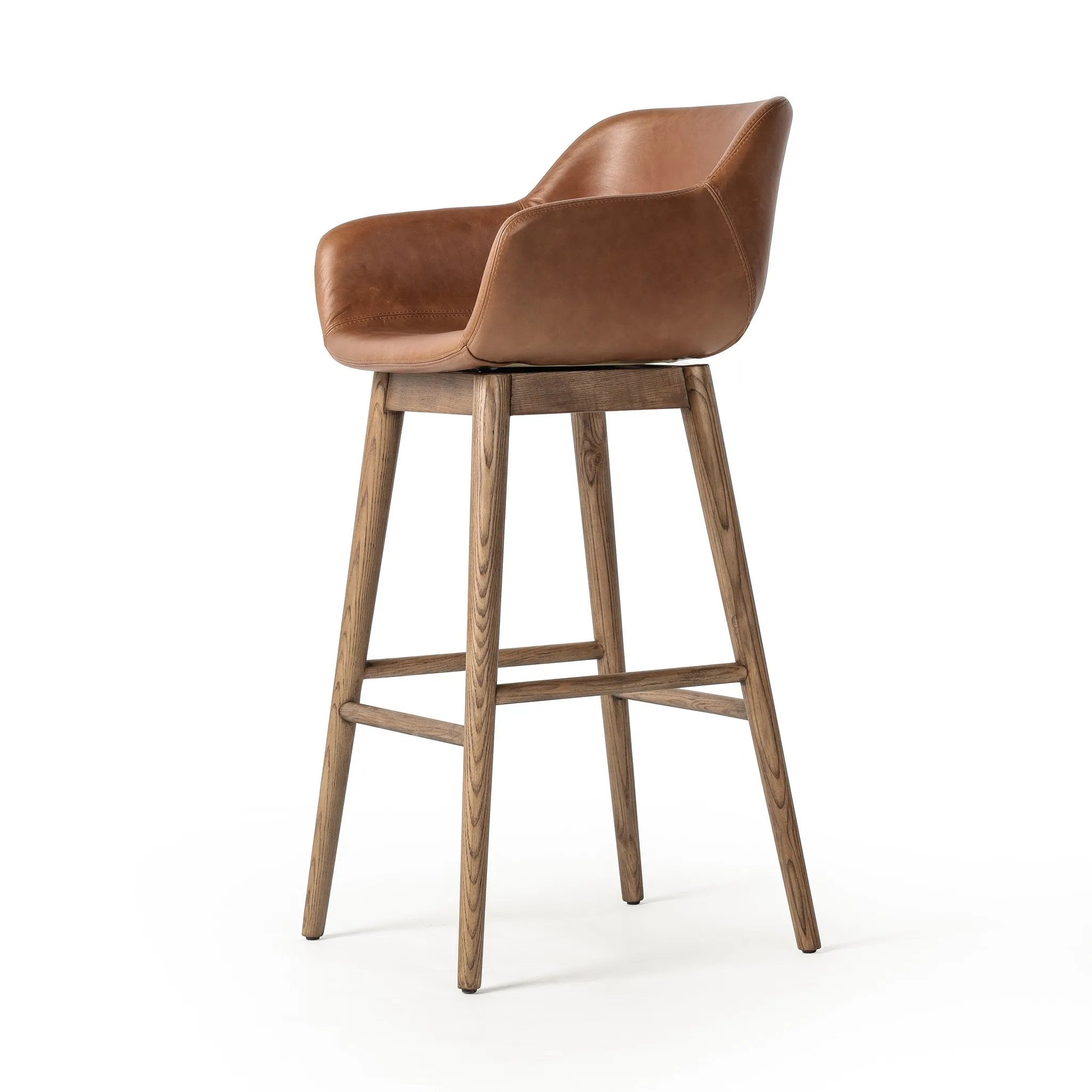 A midcentury-inspired counter stool gets refreshed with a modern memory swivel and chestnut top-grain leather. Slim, tapered oak legs balance a curved seat Amethyst Home provides interior design, new home construction design consulting, vintage area rugs, and lighting in the Boston metro area.