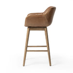 A midcentury-inspired counter stool gets refreshed with a modern memory swivel and chestnut top-grain leather. Slim, tapered oak legs balance a curved seat Amethyst Home provides interior design, new home construction design consulting, vintage area rugs, and lighting in the Houston metro area.