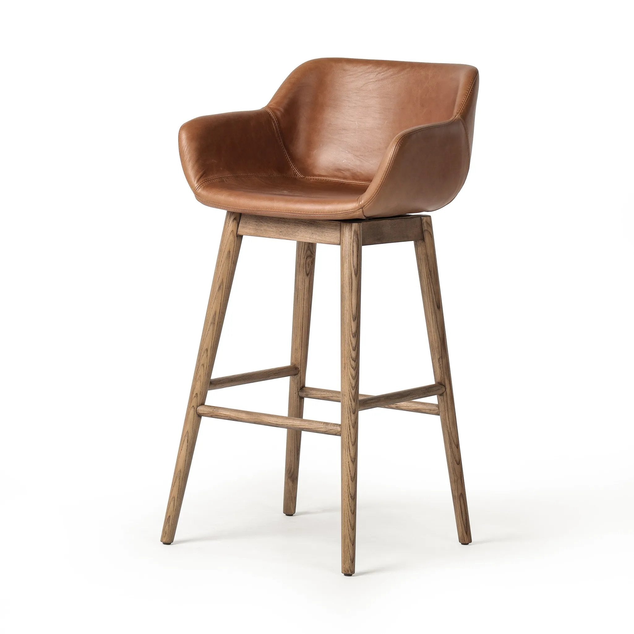A midcentury-inspired counter stool gets refreshed with a modern memory swivel and chestnut top-grain leather. Slim, tapered oak legs balance a curved seat Amethyst Home provides interior design, new home construction design consulting, vintage area rugs, and lighting in the Park City metro area.