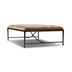 This French Industrialist-inspired cocktail ottoman features a curved stretcher base of bronzed hammered iron and a velvety seat in a versatile earth tone. Style with a sofa or sectional to create an extra surface in your living space, or for bonus seating. Amethyst Home provides interior design, new home construction design consulting, vintage area rugs, and lighting in the Dallas metro area.