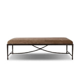 This French Industrialist-inspired cocktail ottoman features a curved stretcher base of bronzed hammered iron and a velvety seat in a versatile earth tone. Style with a sofa or sectional to create an extra surface in your living space, or for bonus seating. Amethyst Home provides interior design, new home construction design consulting, vintage area rugs, and lighting in the Houston metro area.