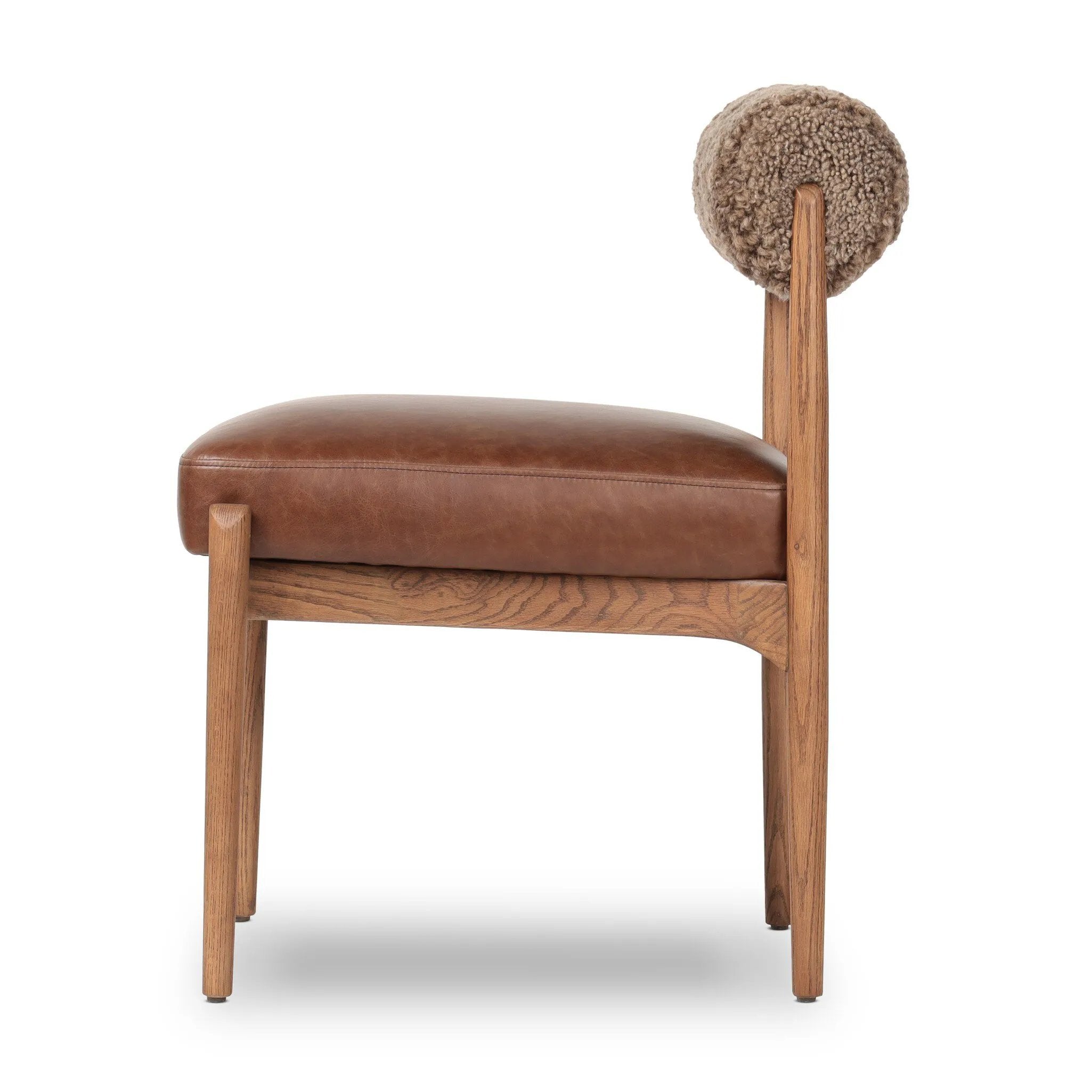 Featuring Jazelle Taupe Shearling Dining Chair by Four Hands at Amethyst Home. The armless dining chair gets a playful update with mixed materials and a bolstered cylinder seat back. Inspired by midcentury and Seventies styling and made from solid oak, top-grain leather  and soft shearling to elevate your bar, kitchen or dining space. Overall Dimensions: 22.25". Amethyst Home provides interior design, new home construction design consulting, vintage area rugs, and lighting in the Tampa metro area.