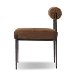 The armless dining chair gets a playful update with a bolstered cylinder seat back. Made from soft shearling and hammered met