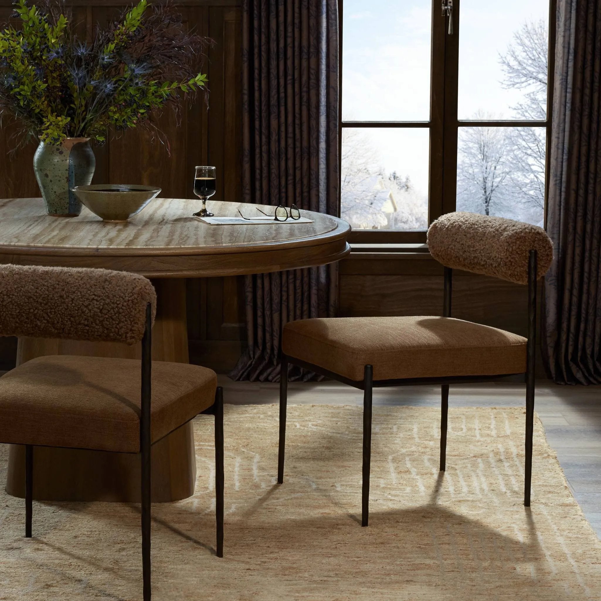 The armless dining chair gets a playful update with a bolstered cylinder seat back. Made from soft shearling and hammered met