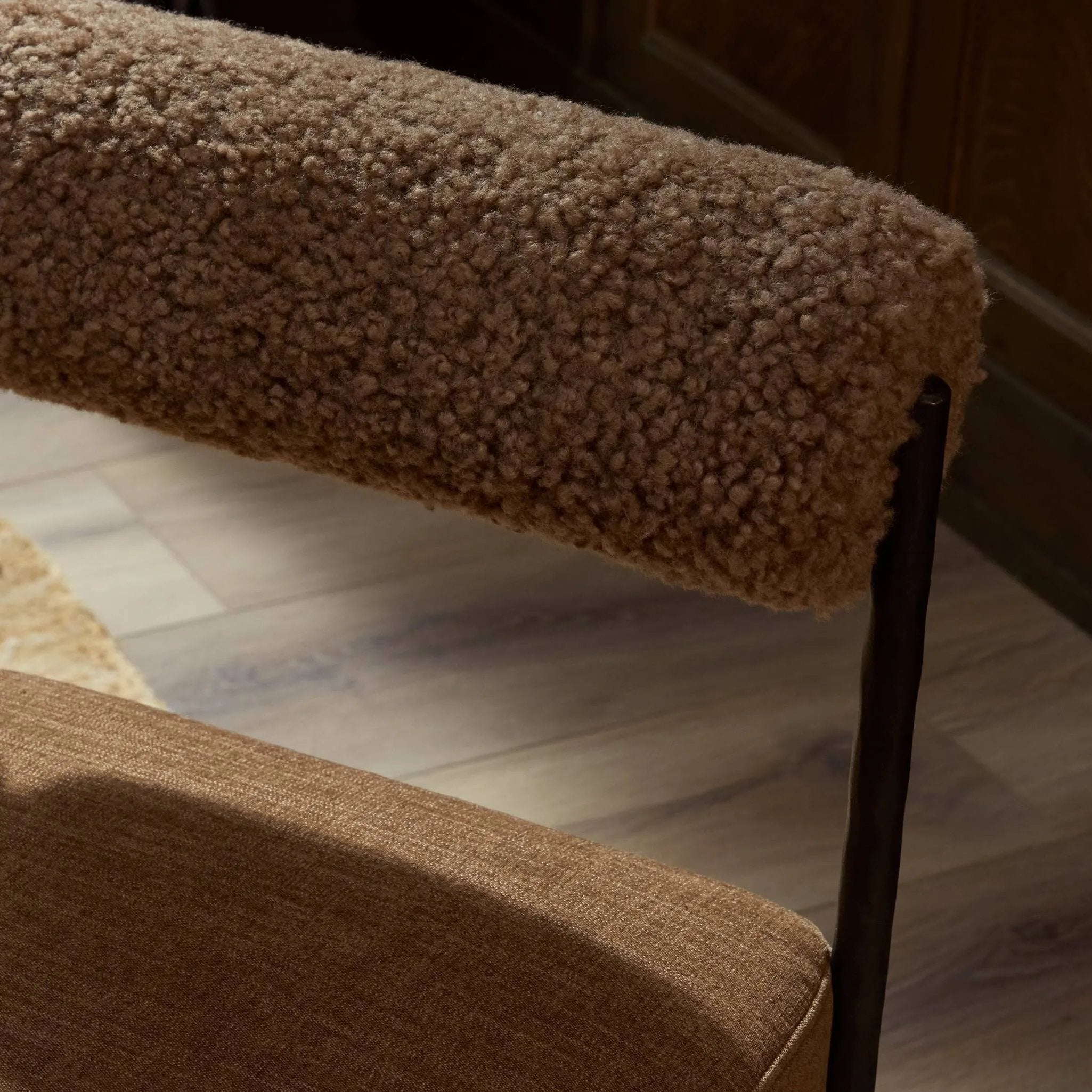 The armless dining chair gets a playful update with a bolstered cylinder seat back. Made from soft shearling and hammered met