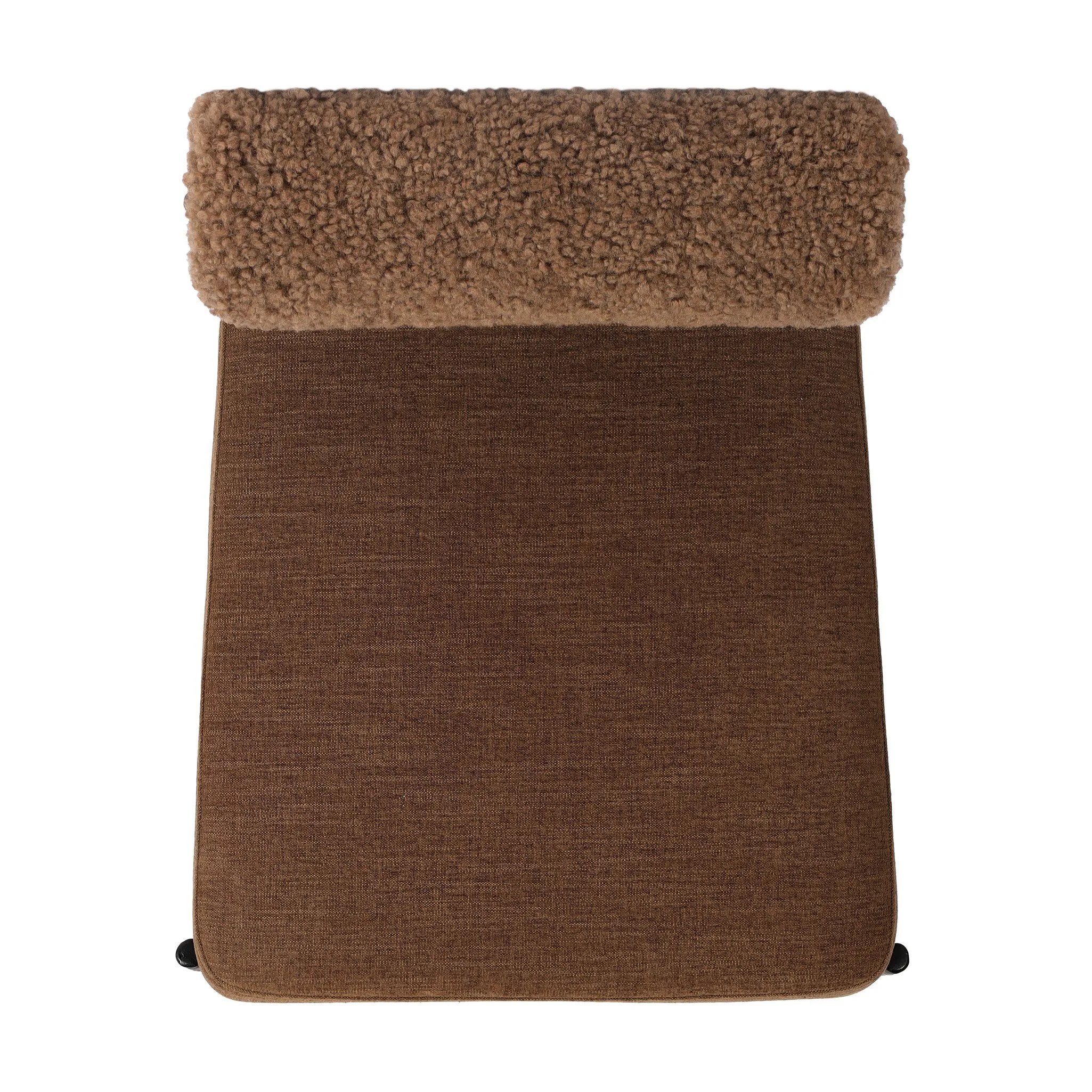 The armless dining chair gets a playful update with a bolstered cylinder seat back. Made from soft shearling and hammered met