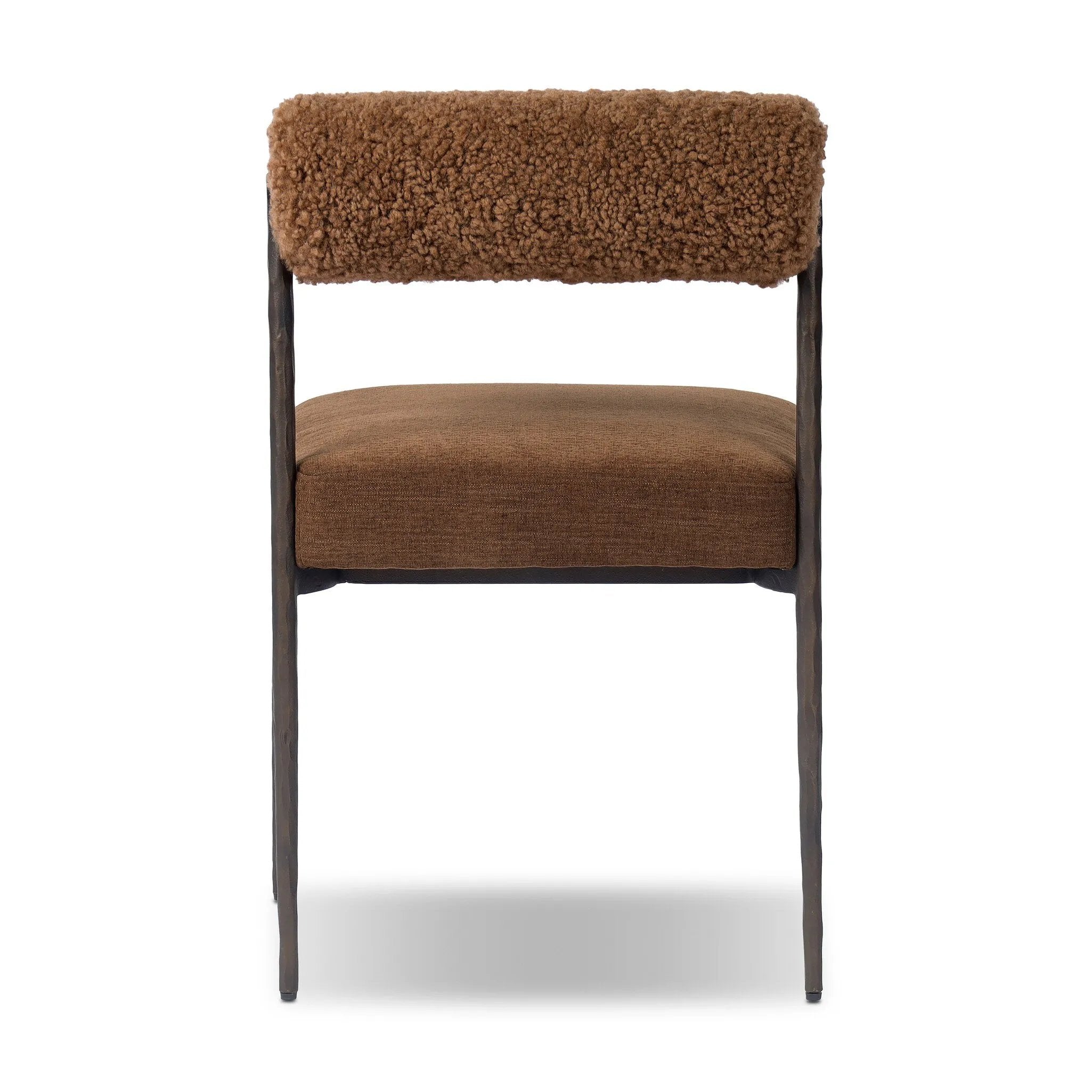 The armless dining chair gets a playful update with a bolstered cylinder seat back. Made from soft shearling and hammered met