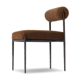 The armless dining chair gets a playful update with a bolstered cylinder seat back. Made from soft shearling and hammered met