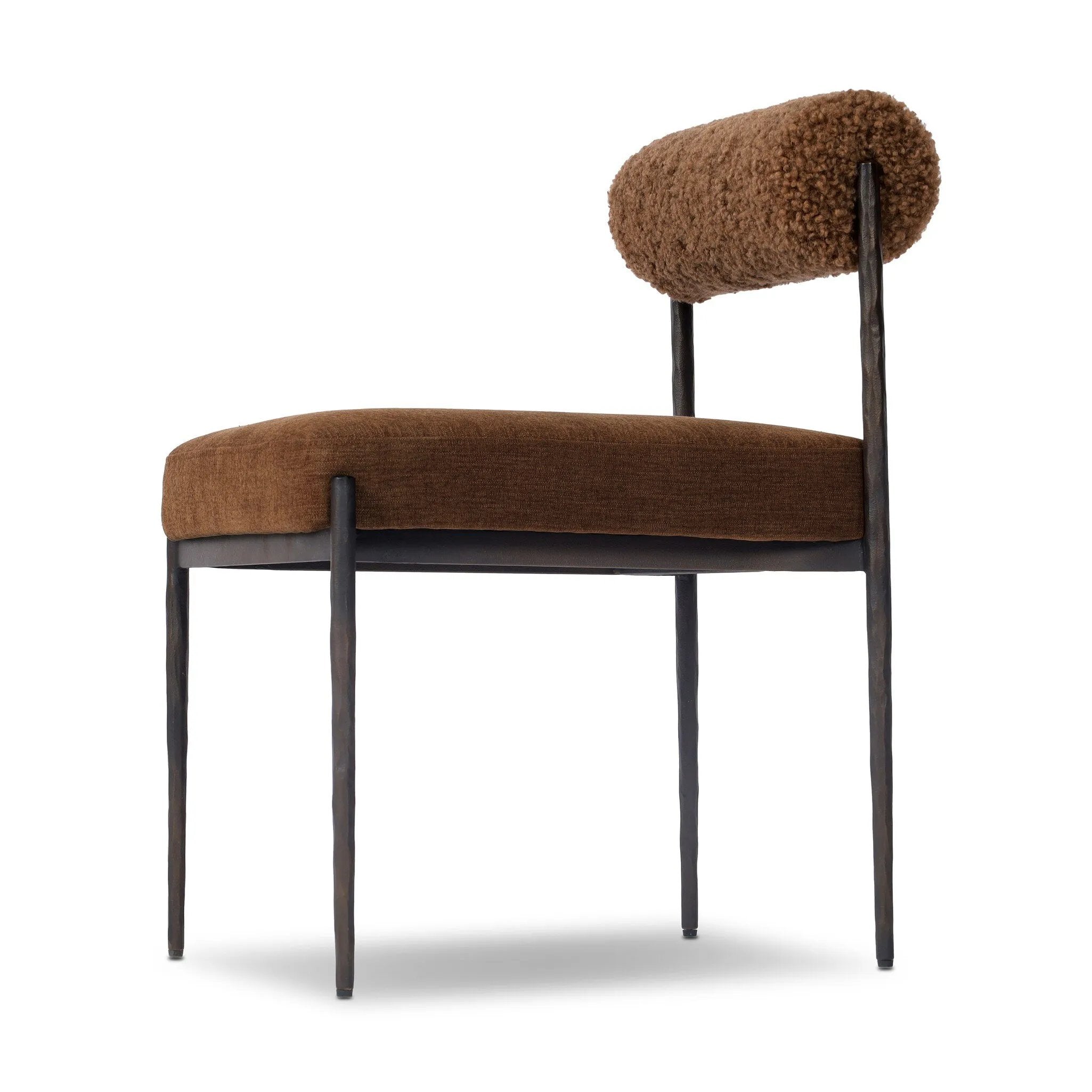 The armless dining chair gets a playful update with a bolstered cylinder seat back. Made from soft shearling and hammered met