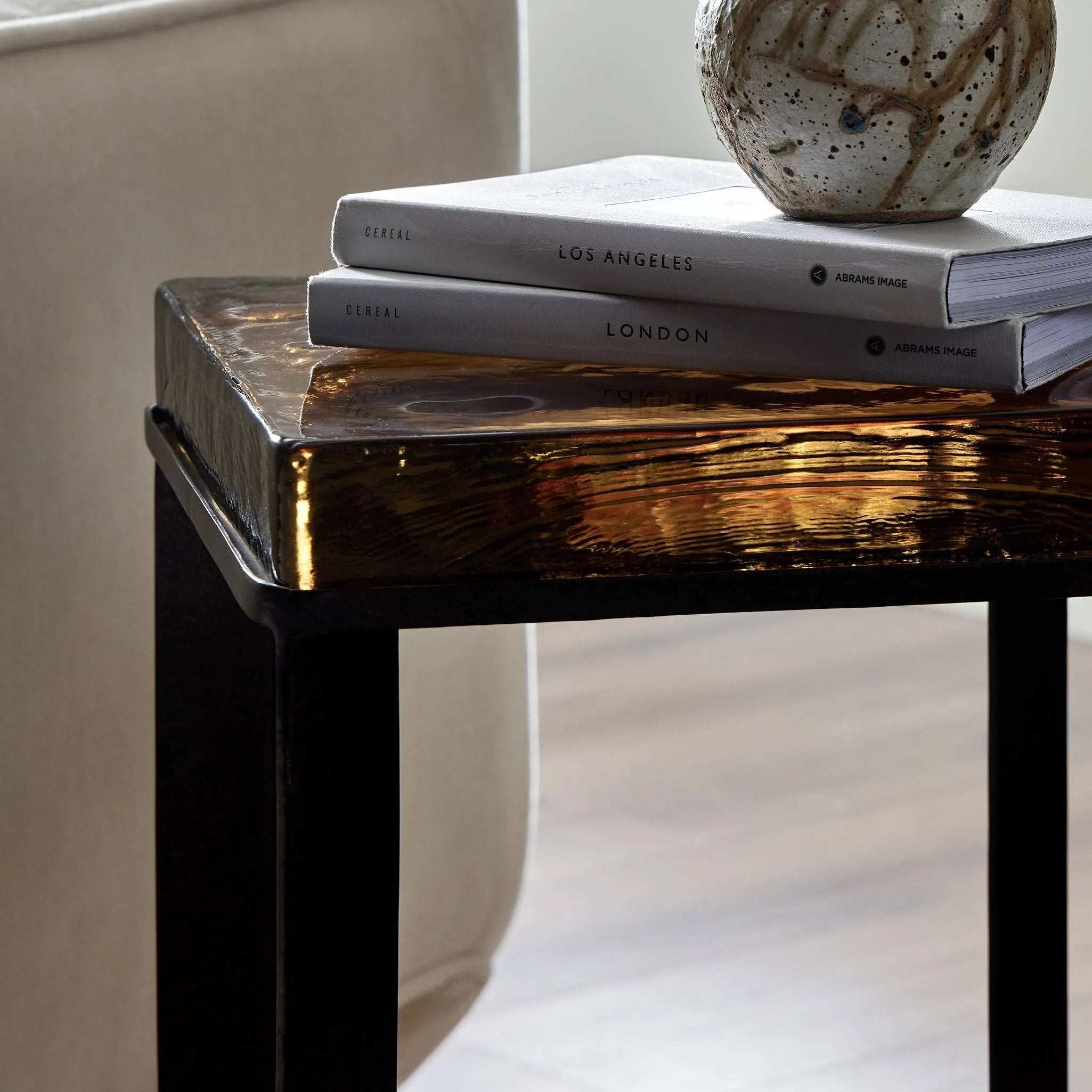 An airy, angular base of charcoal-burnished iron supports a squared tabletop of amber cast glass, perfectly sized to keep your drink or book within reach Amethyst Home provides interior design, new home construction design consulting, vintage area rugs, and lighting in the Kansas City metro area.