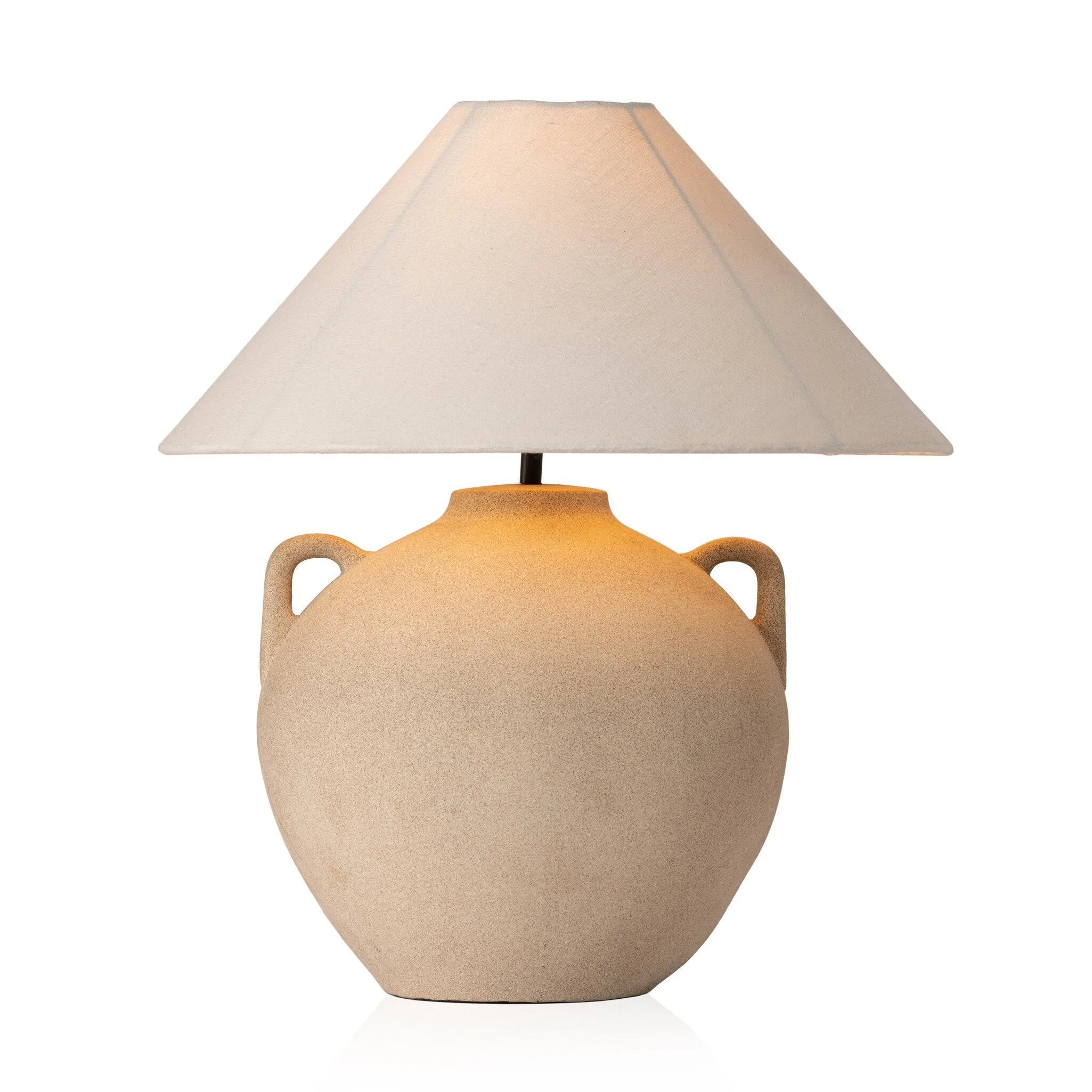 Featuring Mays Light Sand Porcelain Table Lamp by Four Hands at Amethyst Home. Inspired by vintage clay jars, a light sand-colored talavera lamp with handle-like detailing pairs with a tapered linen shade in a versatile ivory. Overall Dimensions: 22.00"w x 22.00"d x 21.00"h
 Shop this lamp at Amethyst - https://www.amethysthome.com/products/mays-light-sand-. Amethyst Home provides interior design, new home construction design consulting, vintage area rugs, and lighting in the Nashville metro area.