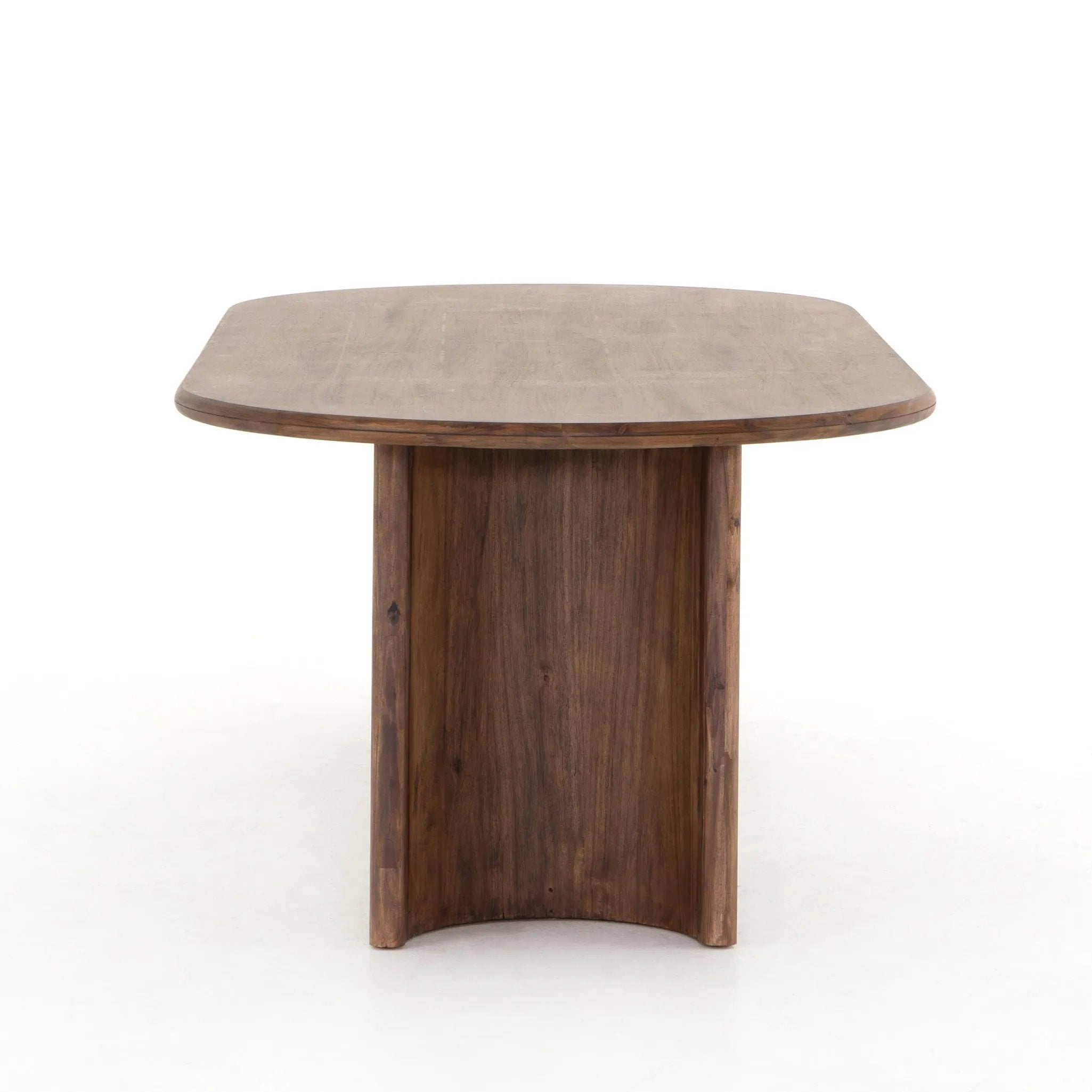 A study in shape. Solid brown acacia forms crescent-shaped legs and sprawling oval tabletop, bringing organic presence to the dining room Amethyst Home provides interior design, new home construction design consulting, vintage area rugs, and lighting in the Houston metro area.
