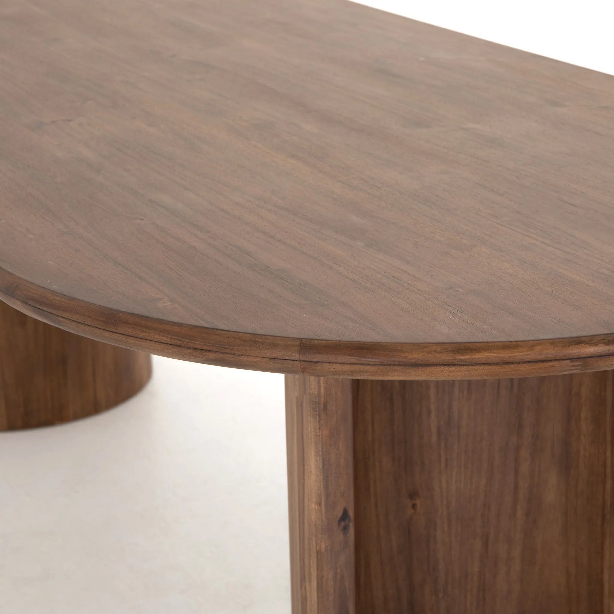 A study in shape. Solid brown acacia forms crescent-shaped legs and sprawling oval tabletop, bringing organic presence to the dining room Amethyst Home provides interior design, new home construction design consulting, vintage area rugs, and lighting in the Nashville metro area.