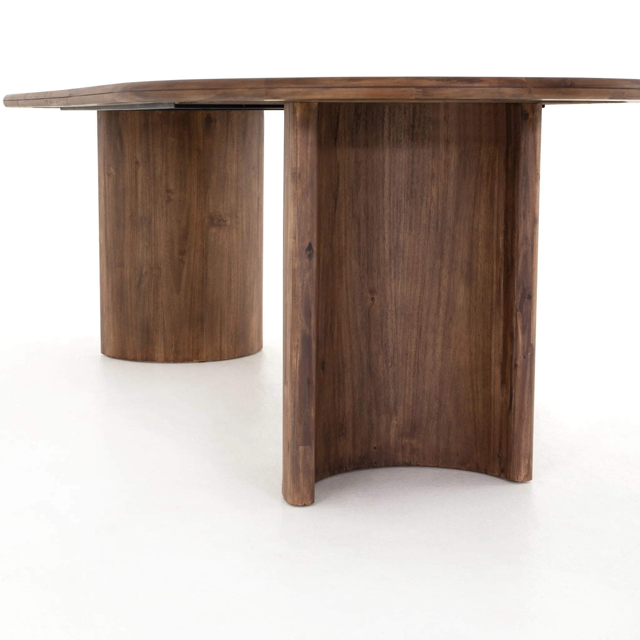 A study in shape. Solid brown acacia forms crescent-shaped legs and sprawling oval tabletop, bringing organic presence to the dining room Amethyst Home provides interior design, new home construction design consulting, vintage area rugs, and lighting in the San Diego metro area.