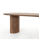 A study in shape. Solid brown acacia forms crescent-shaped legs and sprawling oval tabletop, bringing organic presence to the dining room Amethyst Home provides interior design, new home construction design consulting, vintage area rugs, and lighting in the Seattle metro area.
