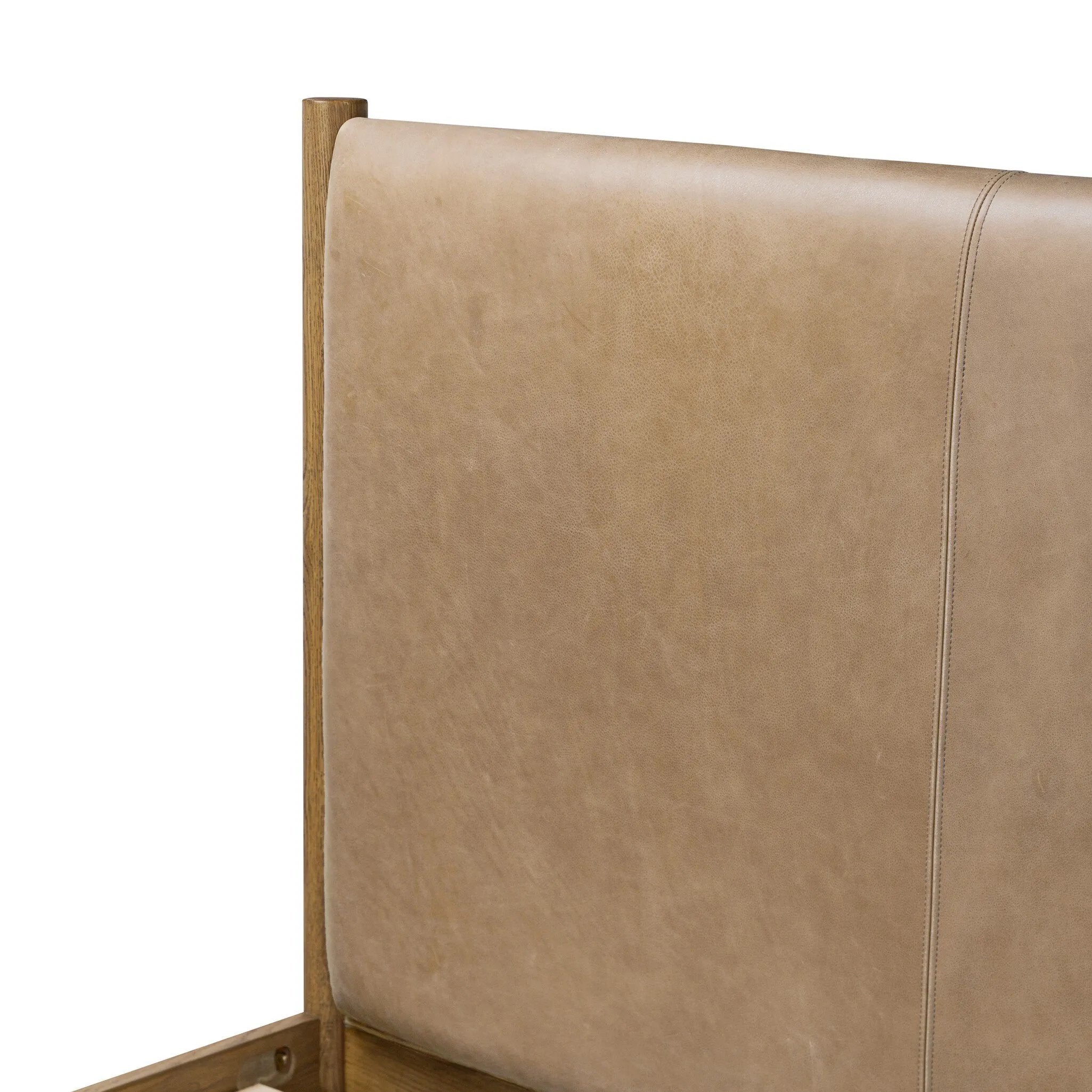 Rounded, chunky dowel legs in an amber oak finish frame the tan top-grain leather headboard of this simple-but-striking bed frame Amethyst Home provides interior design, new home construction design consulting, vintage area rugs, and lighting in the Tampa metro area.