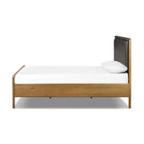 Amber-finished solid oak frames a floating, sling-style headboard made from black top-grain leather, with subtly rounded edges and metal dowel detailing Amethyst Home provides interior design, new home construction design consulting, vintage area rugs, and lighting in the San Diego metro area.