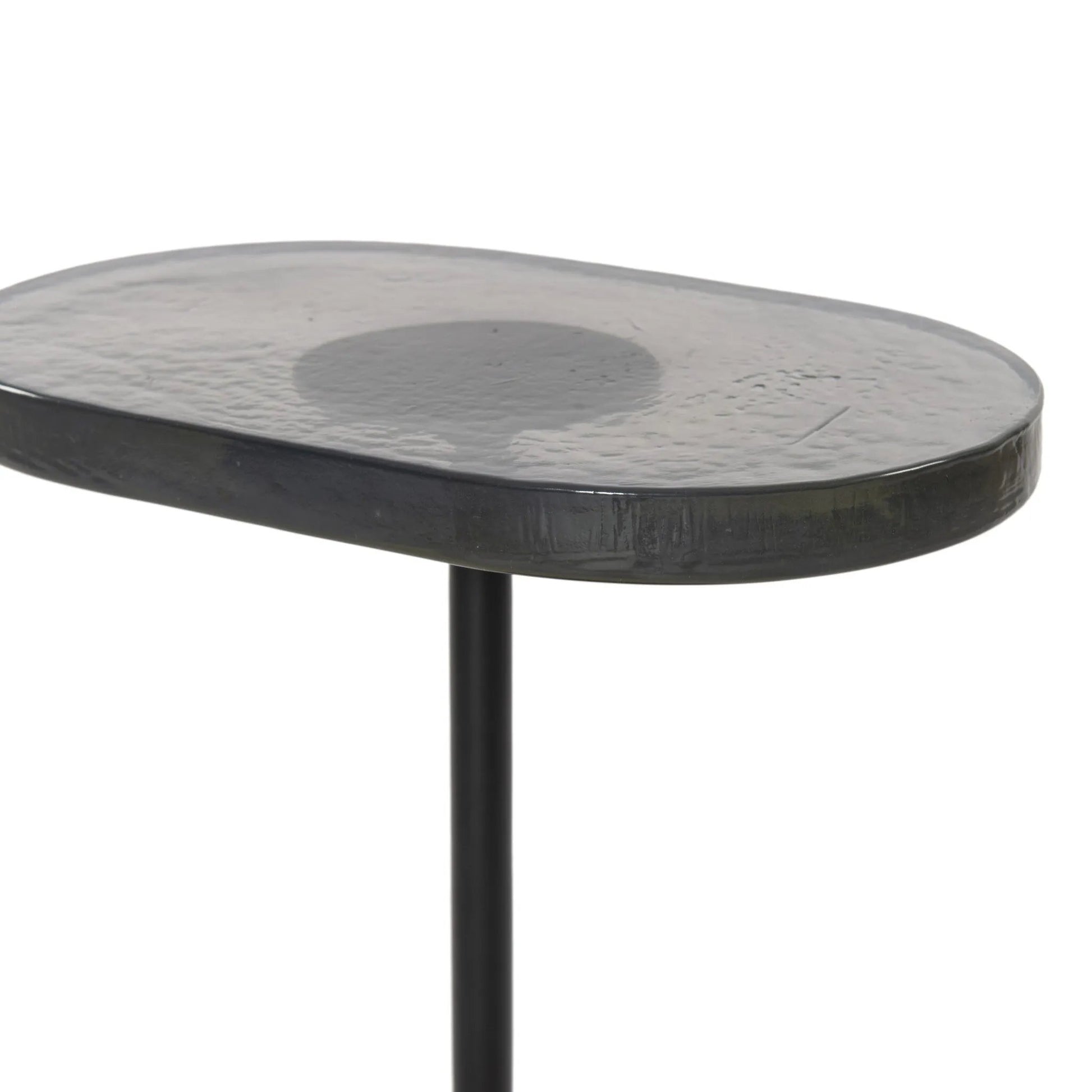 A slim-profile end table pairs a simple iron base with an oval tabletop of hand-cast recycled glass in a soft, smoky blue Amethyst Home provides interior design, new home construction design consulting, vintage area rugs, and lighting in the Dallas metro area.