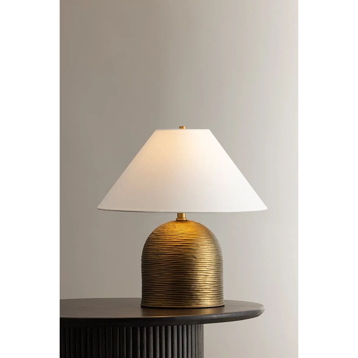 Made in India, Arvin introduces textural depth and warmth to a classic lamp form. There’s a noticeable play of light and shadow across the ridged surface of the domed base, creating movement and dimension. Patina Brass fittings and an off-white linen shade complement the earthy lamp base. Amethyst Home provides interior design, new home construction design consulting, vintage area rugs, and lighting in the Washington metro area.