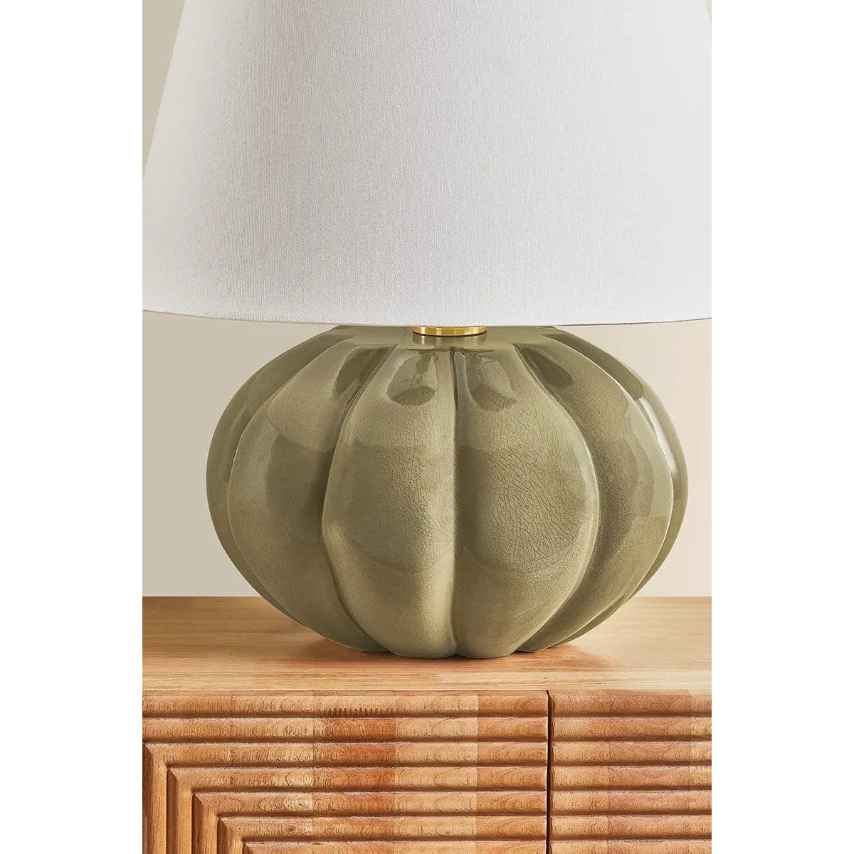 The Beata table lamp makes a sculptural, yet playful statement. A rounded ceramic base, finished in a Harbor Gray Crackle glaze, recalls the shape of a pumpkin. The elongated white linen shade balances the voluminous form, while Aged Brass hardware at the neck adds a polished note. Amethyst Home provides interior design, new home construction design consulting, vintage area rugs, and lighting in the Houston metro area.