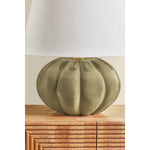 The Beata table lamp makes a sculptural, yet playful statement. A rounded ceramic base, finished in a Harbor Gray Crackle glaze, recalls the shape of a pumpkin. The elongated white linen shade balances the voluminous form, while Aged Brass hardware at the neck adds a polished note. Amethyst Home provides interior design, new home construction design consulting, vintage area rugs, and lighting in the Houston metro area.