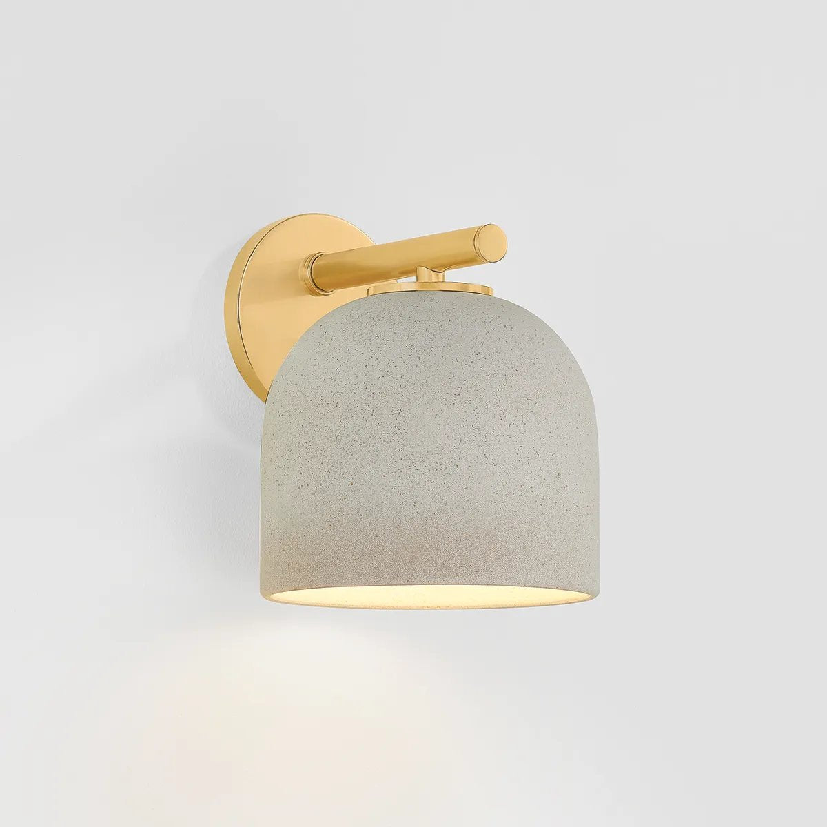 Inspired by Neoclassical architecture, Cara uses a domed shade and textural ceramic finish for a sconce that feels both ancient and new. A matte reactive glaze in an creamy hue creates a subtle surface grain that imitates natural stone. A circular modern armback in an Aged Brass finish adds shine to the fixture.  Amethyst Home provides interior design, new home construction design consulting, vintage area rugs, and lighting in the Charlotte metro area.