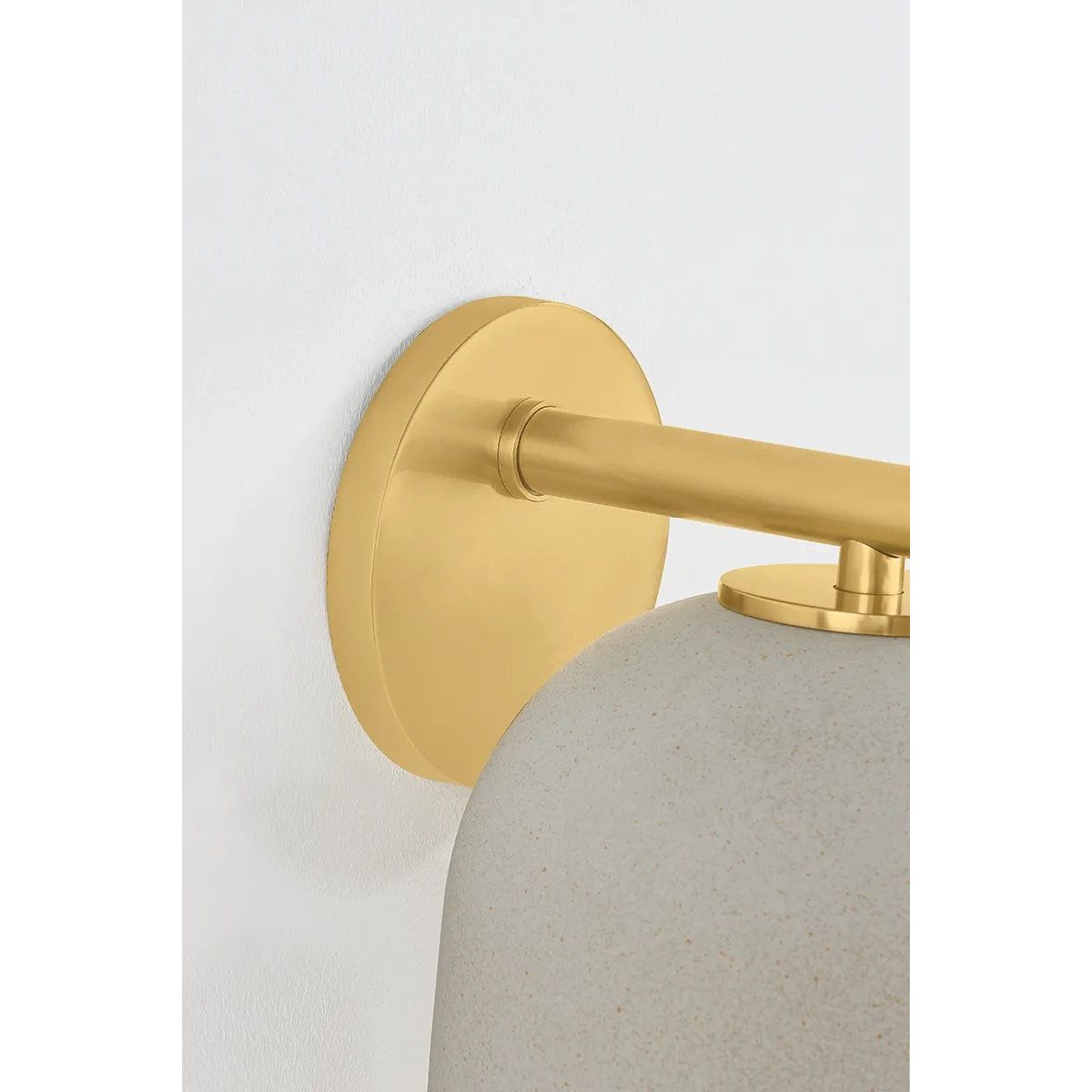 Inspired by Neoclassical architecture, Cara uses a domed shade and textural ceramic finish for a sconce that feels both ancient and new. A matte reactive glaze in an creamy hue creates a subtle surface grain that imitates natural stone. A circular modern armback in an Aged Brass finish adds shine to the fixture.  Amethyst Home provides interior design, new home construction design consulting, vintage area rugs, and lighting in the Winter Garden metro area.